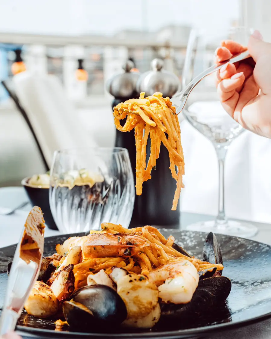 Seafood linguine with mussels and prawns, a glass of white wine alongside